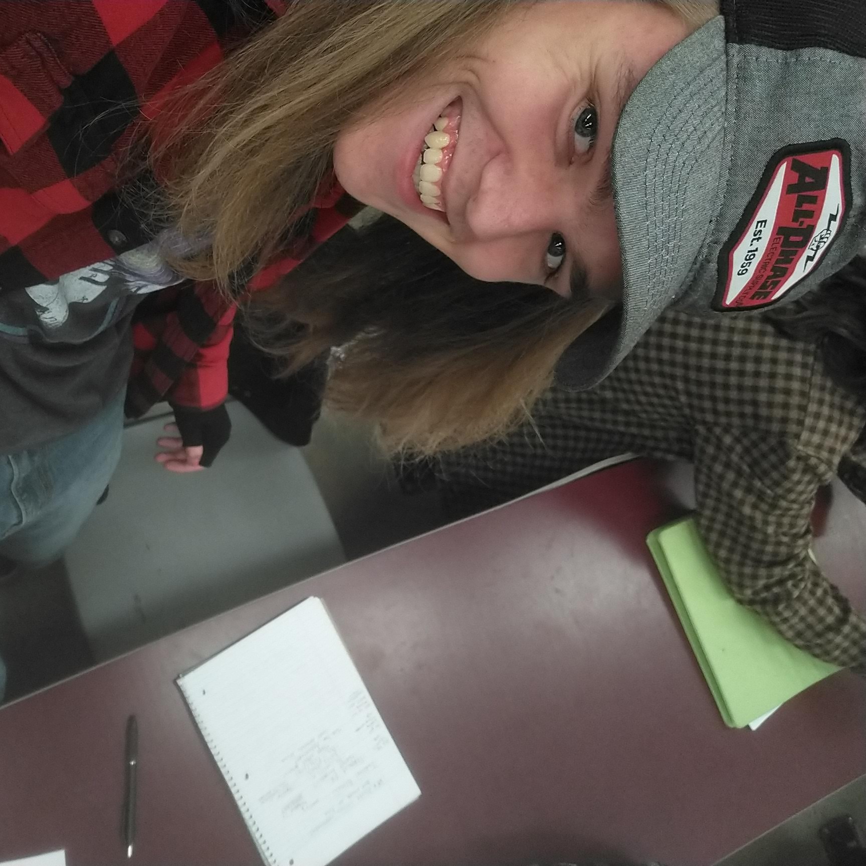 River, wearing a hat and a red flannel. Smiling upwards at the camera.